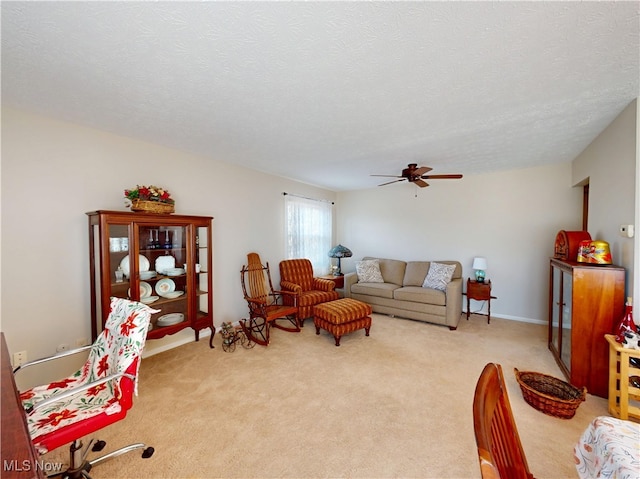 carpeted living area with a ceiling fan and a textured ceiling