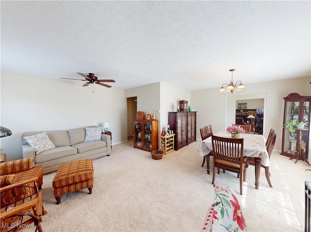 living area featuring ceiling fan with notable chandelier, light colored carpet, and a textured ceiling