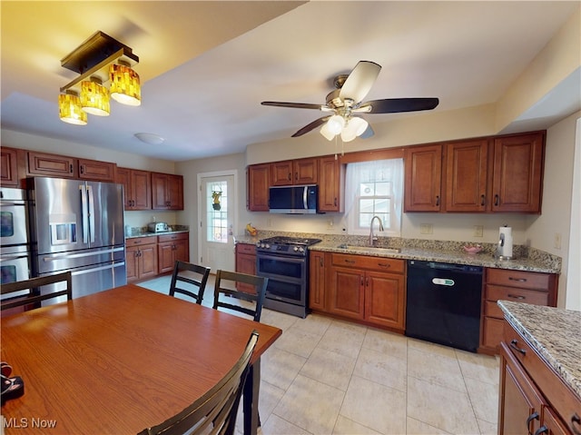 kitchen with ceiling fan, light stone counters, light tile patterned flooring, stainless steel appliances, and a sink