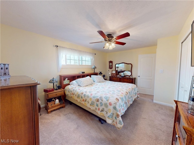 bedroom with light colored carpet, a textured ceiling, baseboards, and ceiling fan