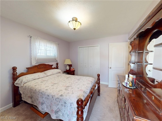 bedroom featuring light colored carpet, a closet, and baseboards