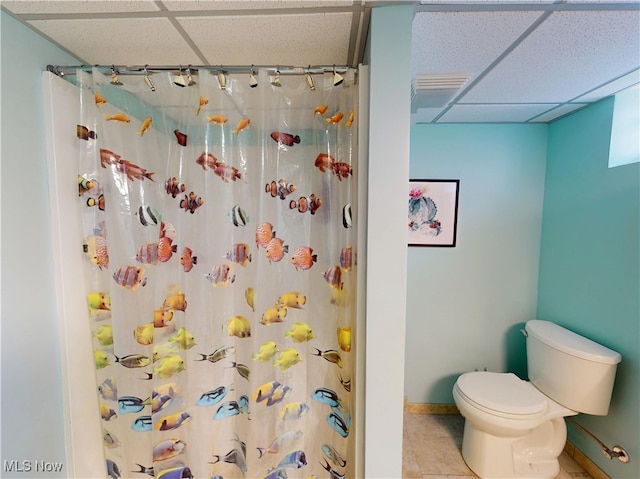 full bathroom with tile patterned floors, toilet, a shower with curtain, a drop ceiling, and baseboards