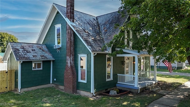 view of front facade featuring a high end roof, fence, covered porch, and a chimney