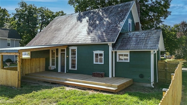 back of house with a shingled roof, a wooden deck, and fence