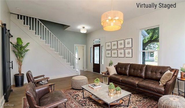 living area with stairs, wood finished floors, a healthy amount of sunlight, and baseboards