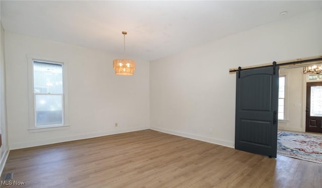 spare room featuring a barn door, wood finished floors, and baseboards