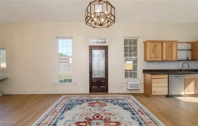 foyer entrance with an inviting chandelier, a wall mounted air conditioner, baseboards, and light wood finished floors