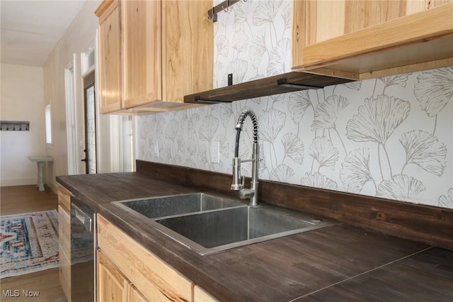 kitchen featuring dishwasher, dark countertops, light brown cabinetry, and a sink