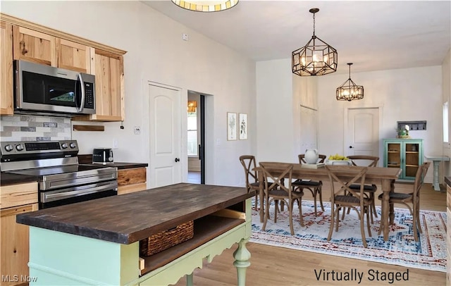 kitchen featuring wood finished floors, light brown cabinets, wooden counters, stainless steel appliances, and decorative backsplash