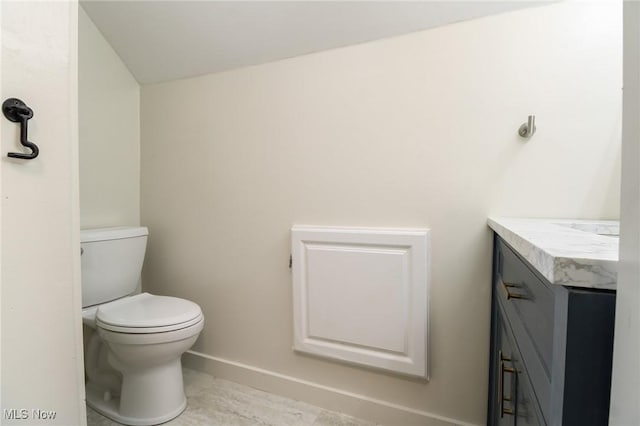 bathroom with toilet, vanity, and baseboards