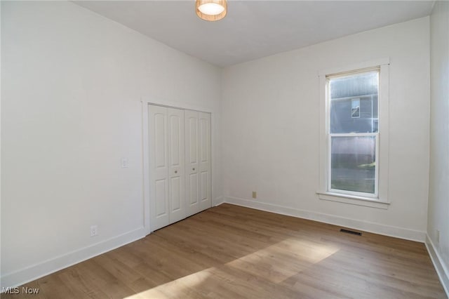 spare room with wood finished floors, visible vents, and baseboards