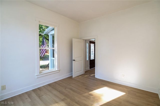 spare room featuring baseboards and wood finished floors