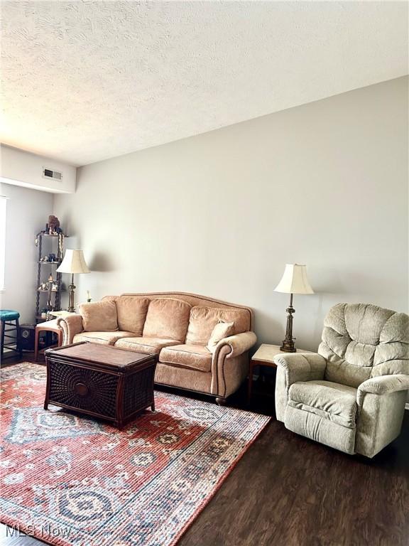 living room with wood finished floors, visible vents, and a textured ceiling