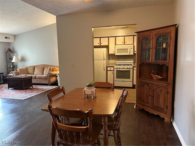 dining space featuring visible vents, baseboards, a textured ceiling, and dark wood finished floors