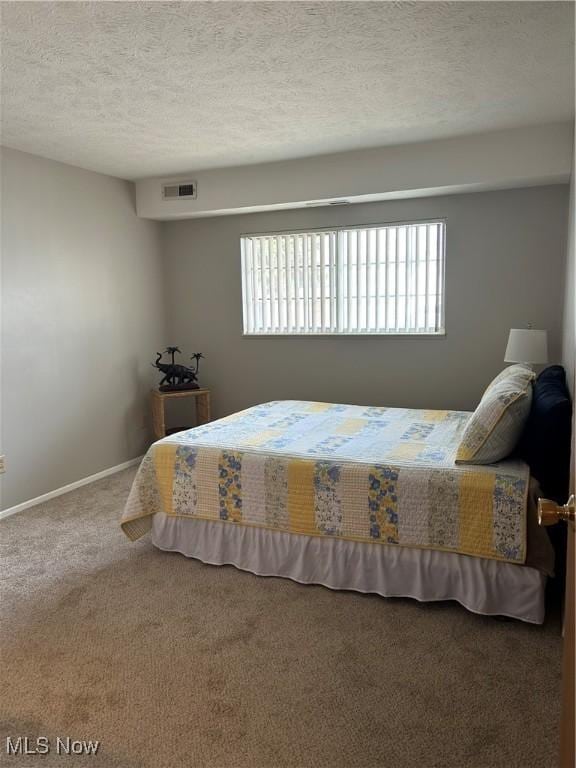 bedroom featuring visible vents, carpet floors, a textured ceiling, and baseboards