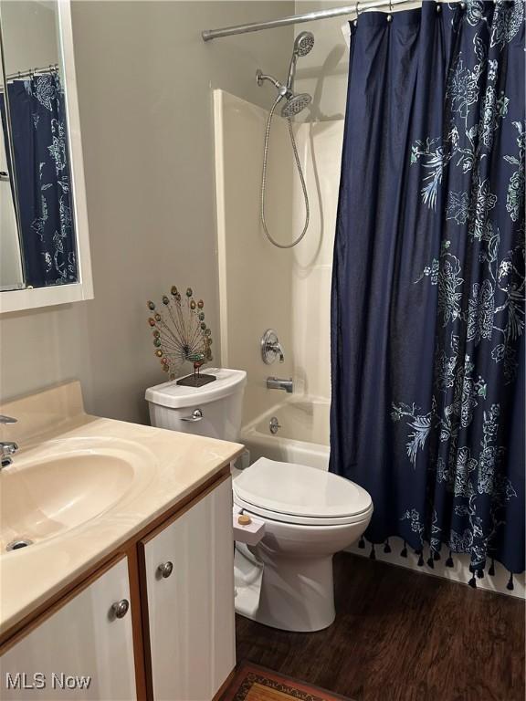 bathroom featuring vanity, toilet, wood finished floors, and shower / tub combo with curtain