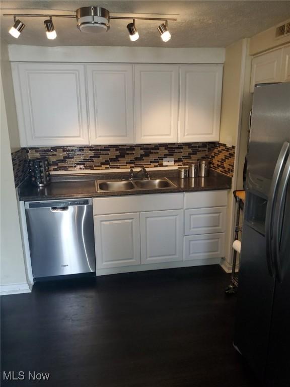 kitchen with visible vents, a sink, dark wood-type flooring, appliances with stainless steel finishes, and white cabinetry