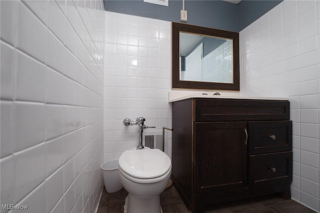 half bath with toilet, tile walls, and vanity