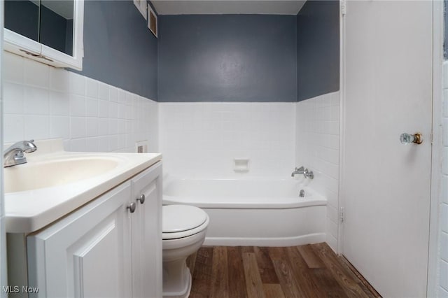 bathroom with a bathtub, toilet, vanity, and wood finished floors