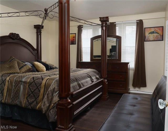 bedroom featuring a baseboard heating unit, dark wood-style flooring, and ornate columns