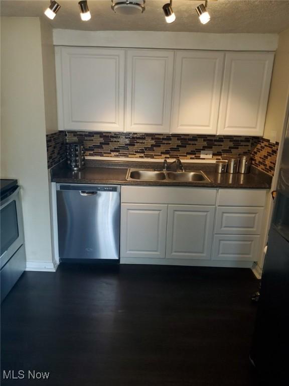 kitchen featuring a sink, dark countertops, white cabinetry, stainless steel appliances, and dark wood-style flooring