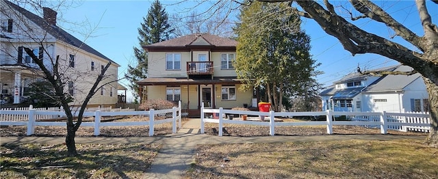 view of front facade featuring a fenced front yard, a balcony, and covered porch