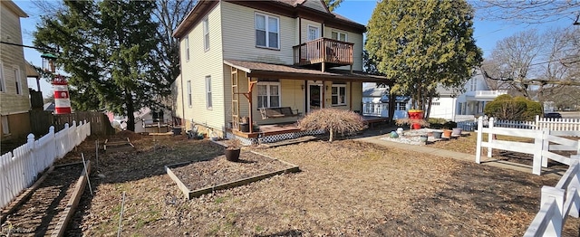 back of property featuring a porch, a balcony, and fence private yard