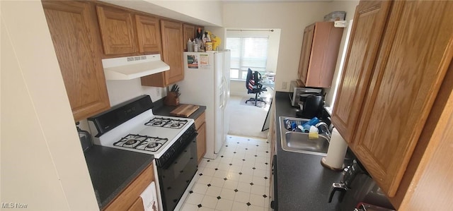 kitchen featuring light floors, range hood, brown cabinetry, gas stove, and a sink