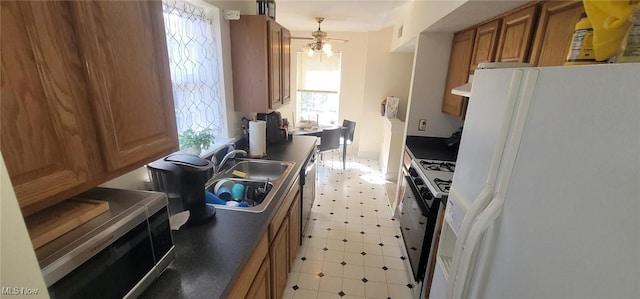 kitchen with brown cabinetry, a sink, white refrigerator with ice dispenser, gas range, and dark countertops