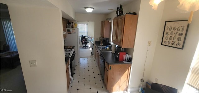 kitchen featuring dark countertops, gas stove, light floors, and a sink