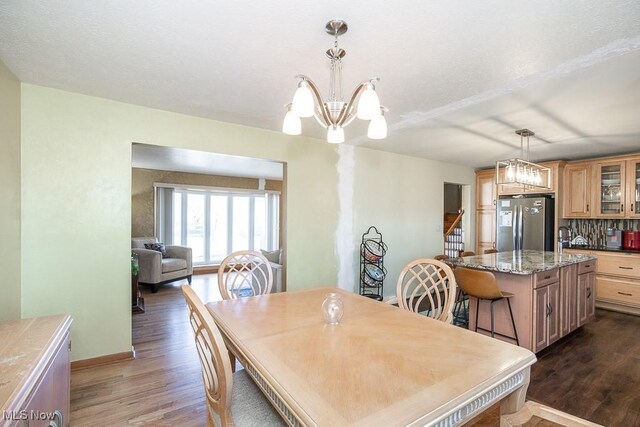 dining area with dark wood finished floors, an inviting chandelier, stairway, and baseboards