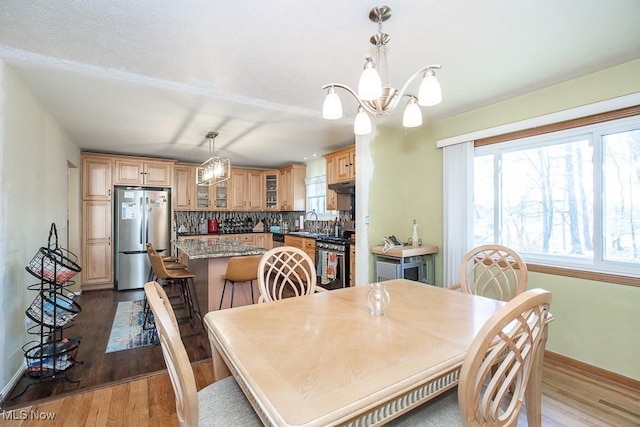 dining space featuring a chandelier, light wood-style flooring, and baseboards