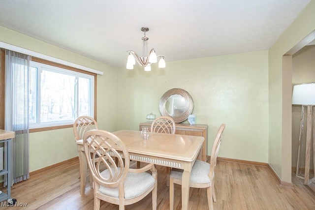 dining space featuring a notable chandelier, baseboards, and light wood-style floors