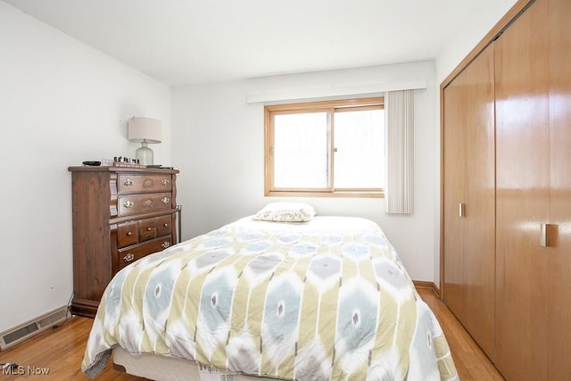 bedroom featuring light wood-style flooring, baseboards, visible vents, and a closet