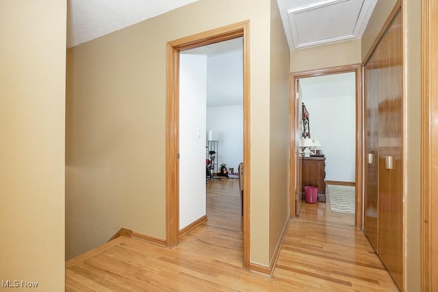 hallway featuring light wood finished floors, attic access, and baseboards