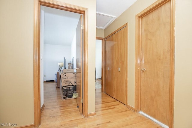 hall with light wood-style floors and attic access