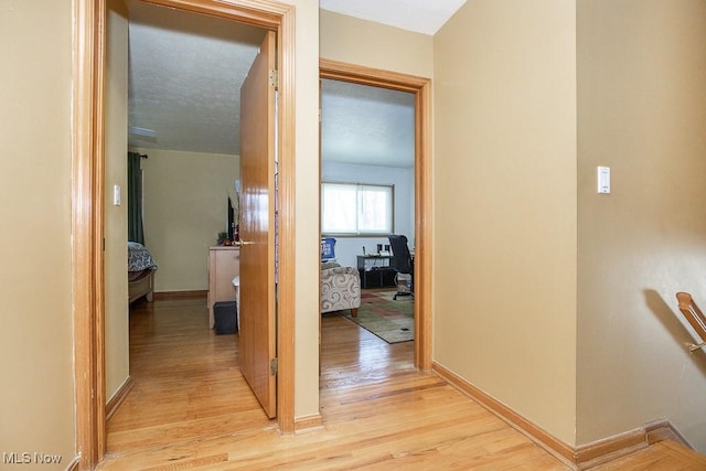 corridor with baseboards and light wood-style flooring