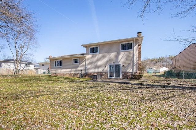 rear view of property with a chimney, a yard, and fence