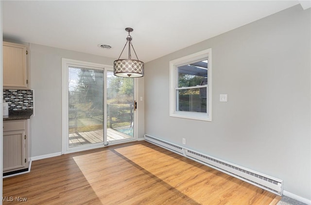 unfurnished dining area with visible vents, wood finished floors, baseboards, and a baseboard radiator