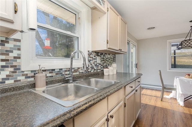 kitchen with visible vents, a sink, tasteful backsplash, dark countertops, and wood finished floors