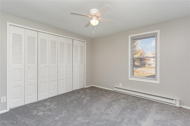 unfurnished bedroom featuring a baseboard heating unit, a closet, carpet floors, baseboards, and ceiling fan