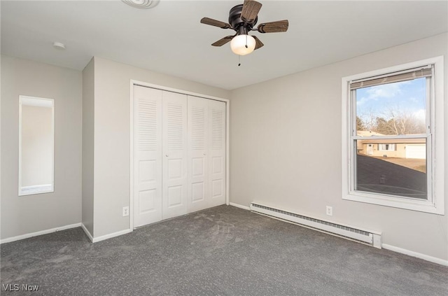 unfurnished bedroom featuring a baseboard heating unit, baseboards, dark colored carpet, and a closet