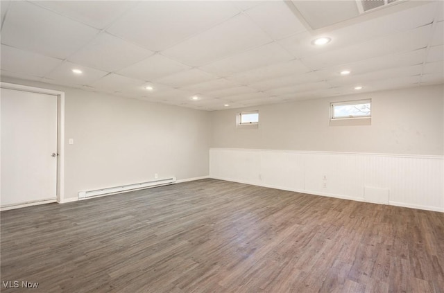 basement with wood finished floors, visible vents, baseboard heating, and a paneled ceiling