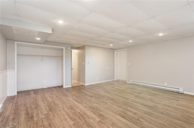 interior space featuring light wood-type flooring, visible vents, a drop ceiling, recessed lighting, and baseboard heating