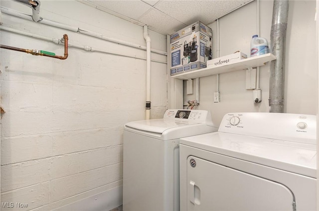 clothes washing area featuring washer and dryer, laundry area, and concrete block wall