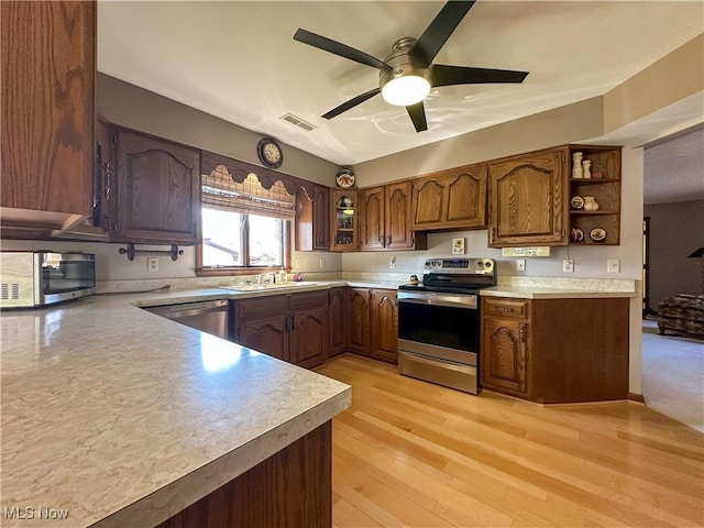 kitchen with visible vents, light wood-style flooring, a sink, stainless steel appliances, and light countertops