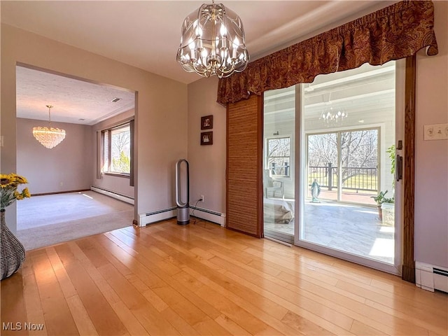 unfurnished dining area featuring light wood-style flooring, baseboard heating, and a chandelier