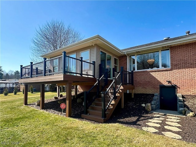 rear view of property with brick siding, a lawn, a wooden deck, and stairs