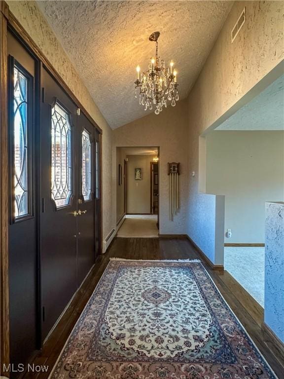 foyer featuring wood finished floors, visible vents, an inviting chandelier, vaulted ceiling, and a textured ceiling