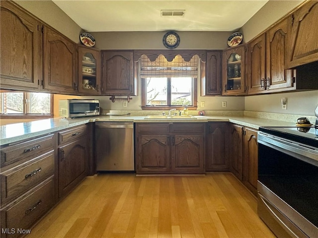 kitchen with visible vents, a sink, appliances with stainless steel finishes, light wood finished floors, and light countertops